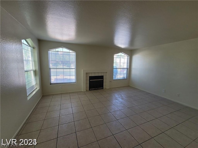 unfurnished living room with light tile patterned floors, a tile fireplace, and a textured ceiling