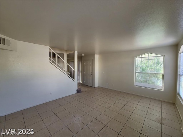 spare room featuring light tile patterned floors and a textured ceiling