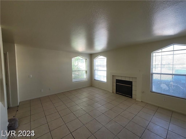 unfurnished living room with a textured ceiling, a tile fireplace, and light tile patterned flooring