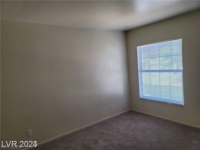 empty room featuring dark colored carpet and a wealth of natural light