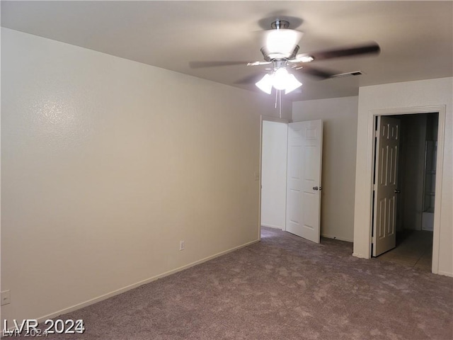 unfurnished bedroom with ceiling fan, connected bathroom, and dark carpet