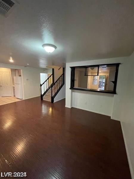 unfurnished living room featuring a textured ceiling and hardwood / wood-style floors