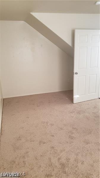 additional living space featuring lofted ceiling and carpet flooring