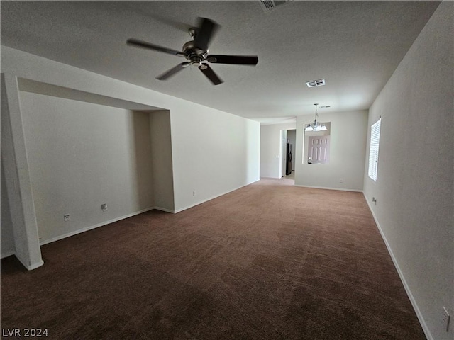 unfurnished living room with a textured ceiling, dark colored carpet, and ceiling fan with notable chandelier