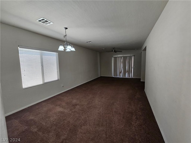 carpeted spare room featuring ceiling fan with notable chandelier