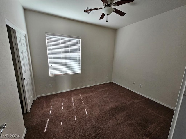 unfurnished room with ceiling fan and dark carpet