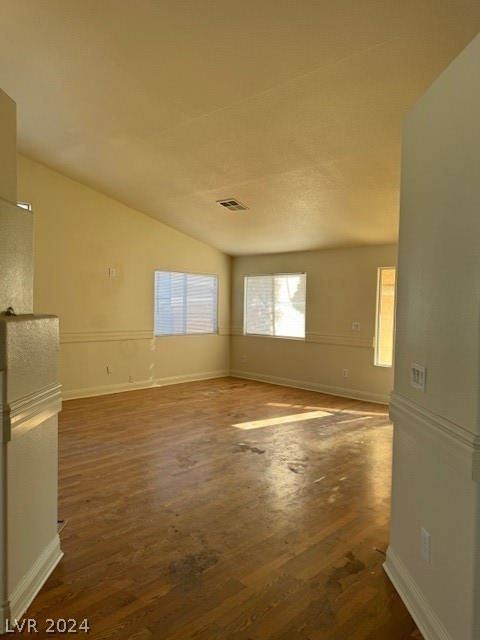 empty room featuring vaulted ceiling and dark wood-type flooring