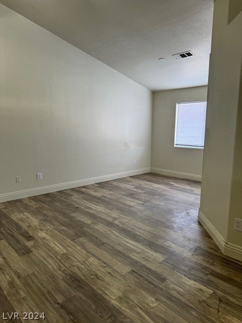 empty room featuring a textured ceiling and dark hardwood / wood-style floors