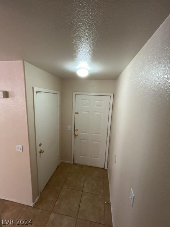 entryway featuring light tile patterned floors and a textured ceiling