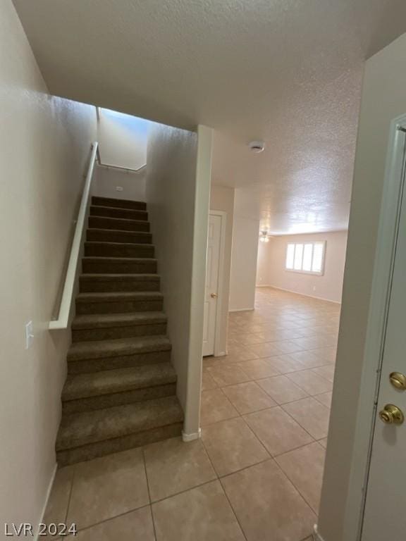 stairway with tile patterned flooring and a textured ceiling