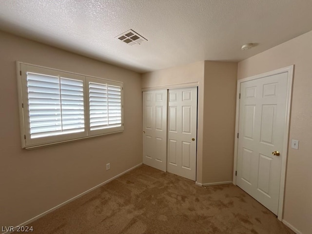 unfurnished bedroom featuring a textured ceiling, carpet floors, and a closet