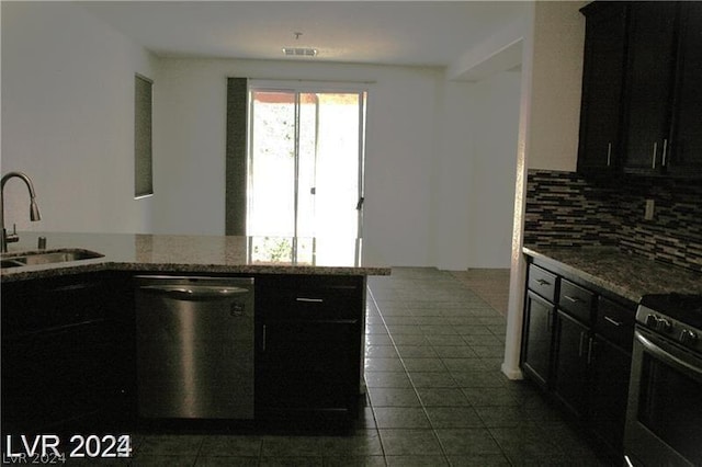 kitchen with light stone countertops, sink, backsplash, and stainless steel appliances