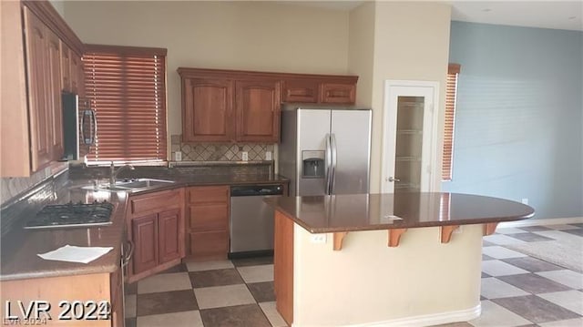 kitchen featuring appliances with stainless steel finishes, a center island, a kitchen bar, tasteful backsplash, and sink