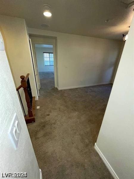 hall with dark colored carpet