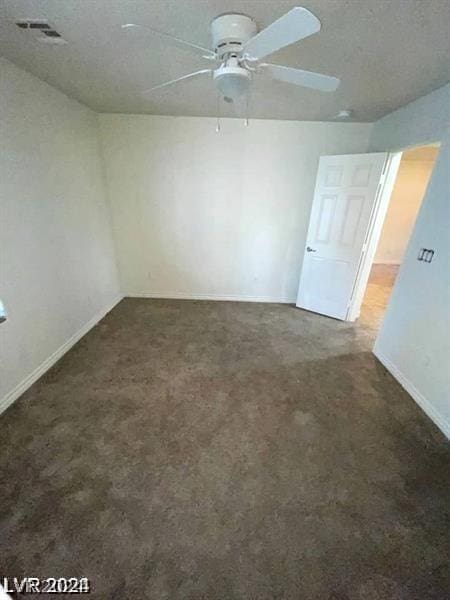 spare room featuring ceiling fan and dark colored carpet