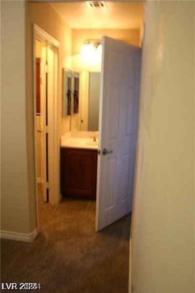 corridor with sink and dark carpet