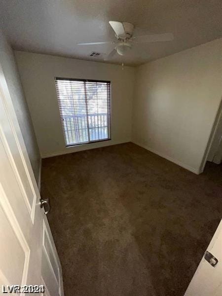 unfurnished room featuring dark colored carpet and ceiling fan