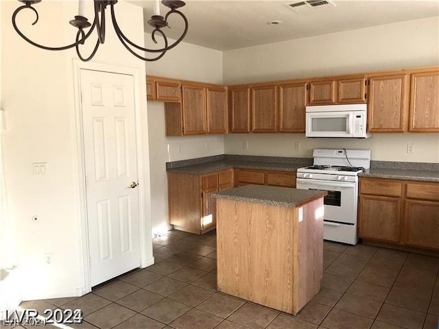 kitchen with a kitchen island, dark tile patterned floors, and white appliances