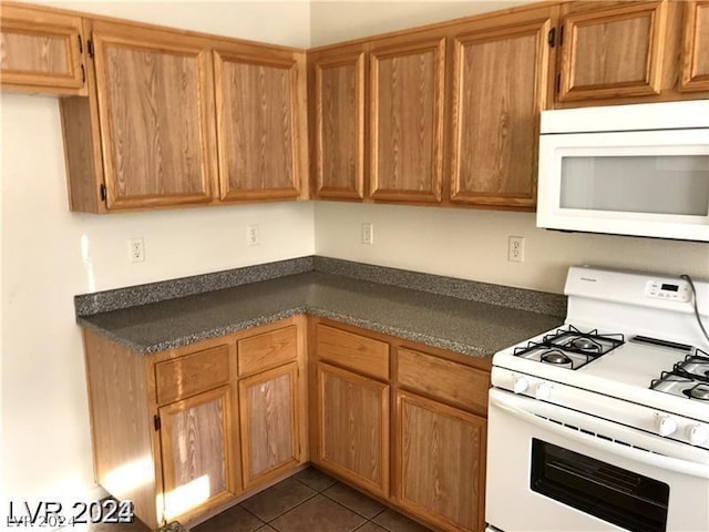 kitchen featuring dark tile patterned floors and white appliances