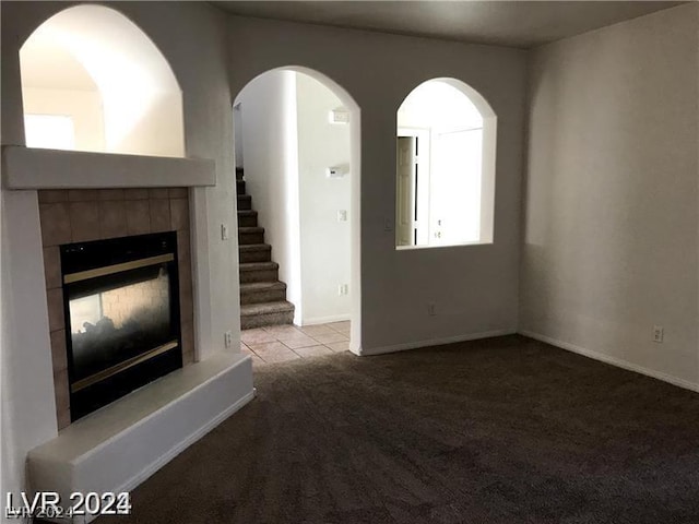 unfurnished living room with light colored carpet and a tiled fireplace