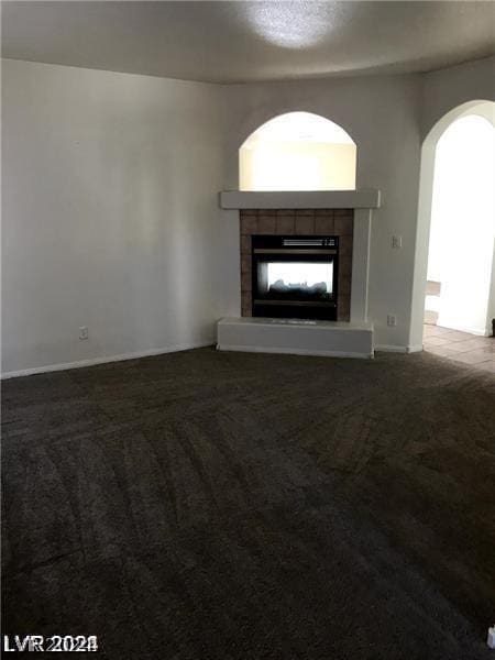 unfurnished living room featuring a tiled fireplace and carpet flooring