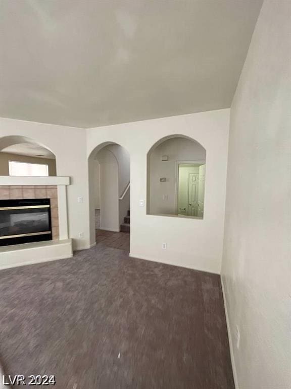 unfurnished living room featuring a tile fireplace and carpet flooring