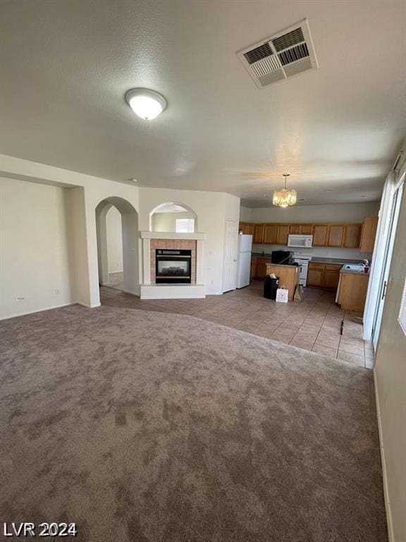 unfurnished living room with a textured ceiling, a tile fireplace, and light carpet