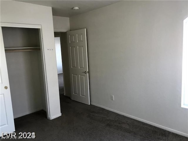 unfurnished bedroom featuring a closet and dark colored carpet