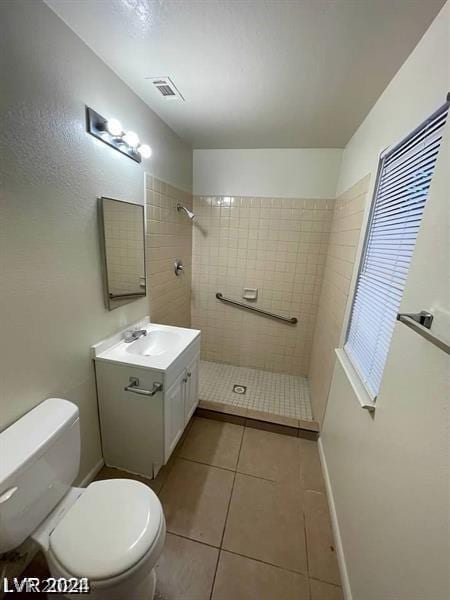 bathroom featuring toilet, vanity, tile patterned flooring, and tiled shower