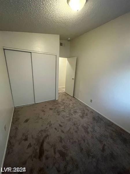 unfurnished bedroom featuring carpet floors, a textured ceiling, and a closet