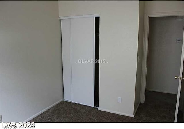 unfurnished bedroom featuring a closet and dark colored carpet