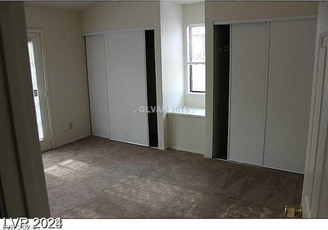 unfurnished bedroom with two closets and carpet flooring