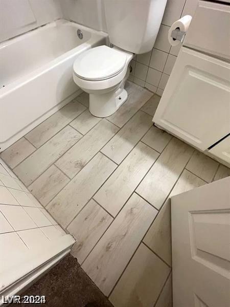 bathroom with toilet, tile walls, and tile patterned floors