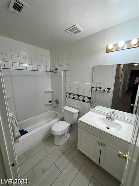 full bathroom featuring toilet, bathing tub / shower combination, tile patterned flooring, tile walls, and vanity