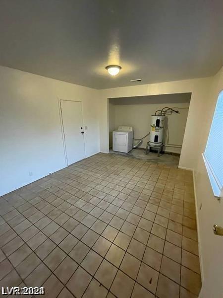 spare room with light tile patterned floors, water heater, and washer / clothes dryer