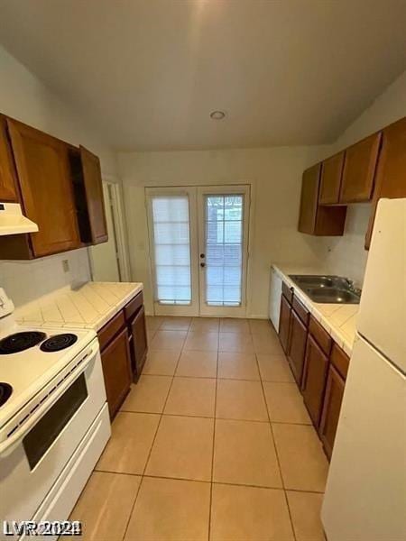 kitchen featuring tile countertops, sink, white appliances, light tile patterned floors, and french doors