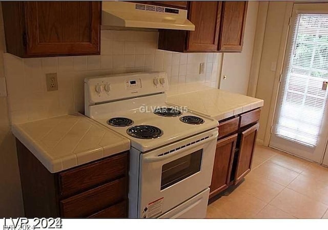 kitchen featuring white electric range, tile countertops, and light tile patterned flooring