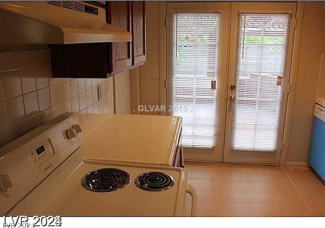 kitchen with white range with electric stovetop, tasteful backsplash, french doors, and light tile patterned flooring