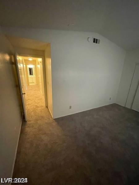 carpeted spare room featuring vaulted ceiling