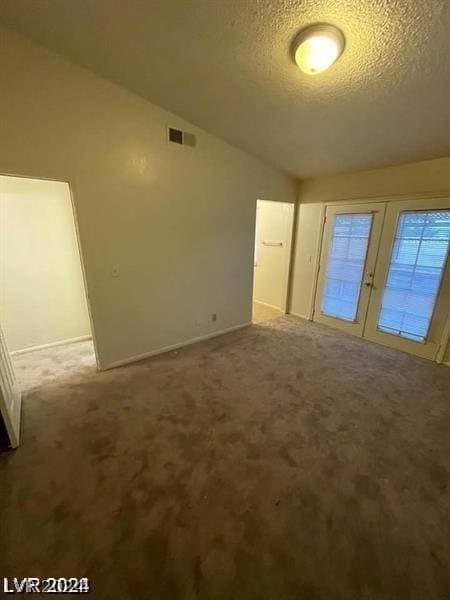 unfurnished bedroom featuring lofted ceiling, light colored carpet, and a textured ceiling