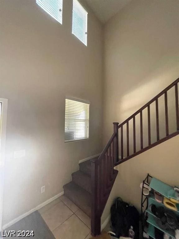 staircase featuring tile patterned floors and a towering ceiling