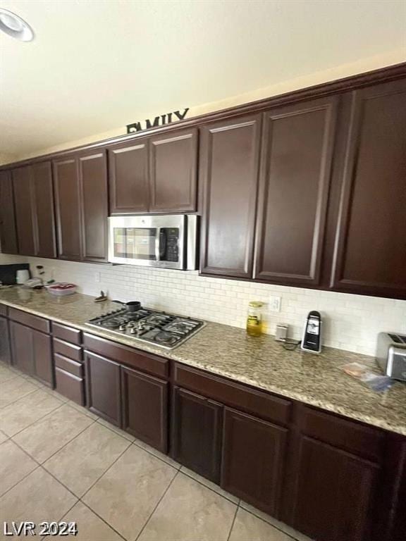 kitchen featuring light tile patterned floors, appliances with stainless steel finishes, and dark brown cabinets