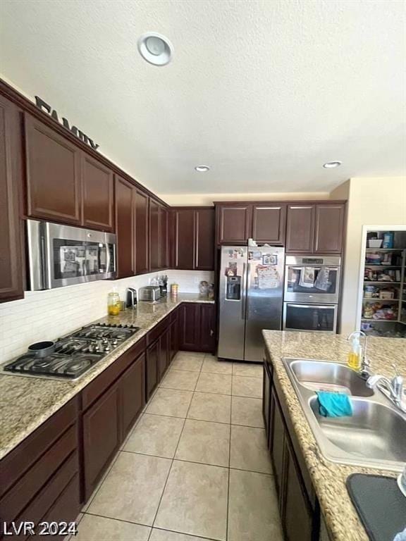 kitchen featuring light tile patterned floors, sink, light stone counters, and stainless steel appliances