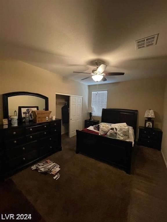 bedroom featuring ceiling fan, a spacious closet, a closet, and dark colored carpet