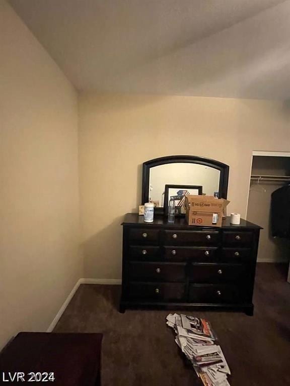 bedroom featuring lofted ceiling, a closet, and dark carpet