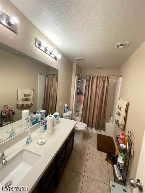 full bathroom with a textured ceiling, tile patterned floors, vanity, shower / tub combo, and toilet