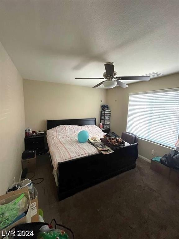 bedroom with ceiling fan and dark colored carpet