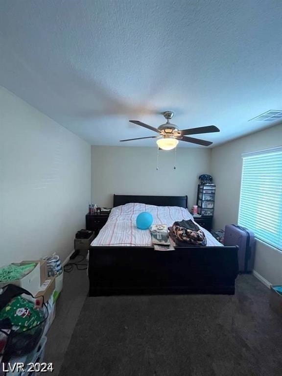 unfurnished bedroom with ceiling fan, a textured ceiling, and dark colored carpet