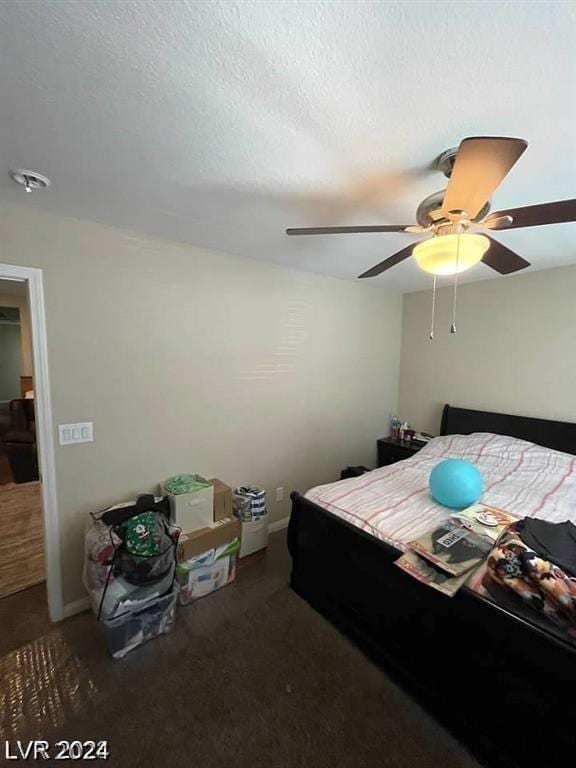 carpeted bedroom featuring ceiling fan and a textured ceiling