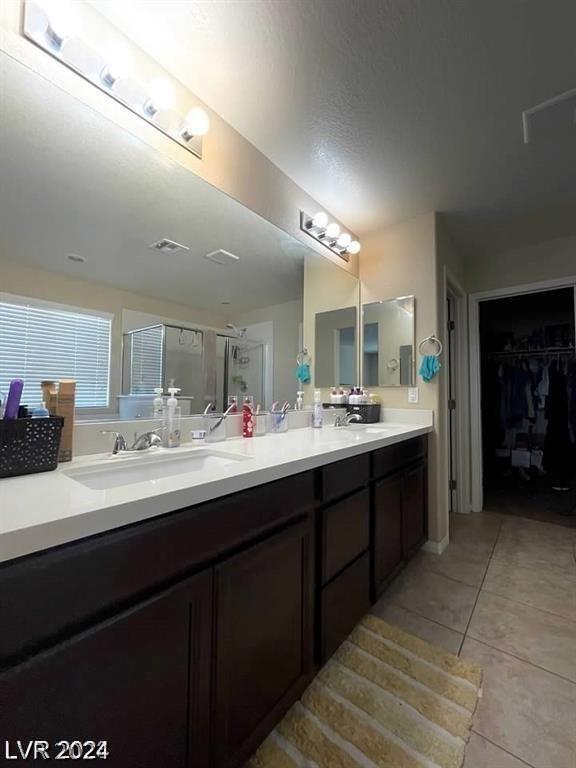 bathroom featuring a shower with shower door, vanity, and tile patterned flooring